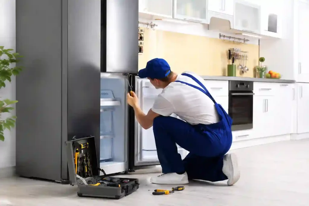 Professional technician providing refrigerator repair in Bahrain in a modern kitchen.