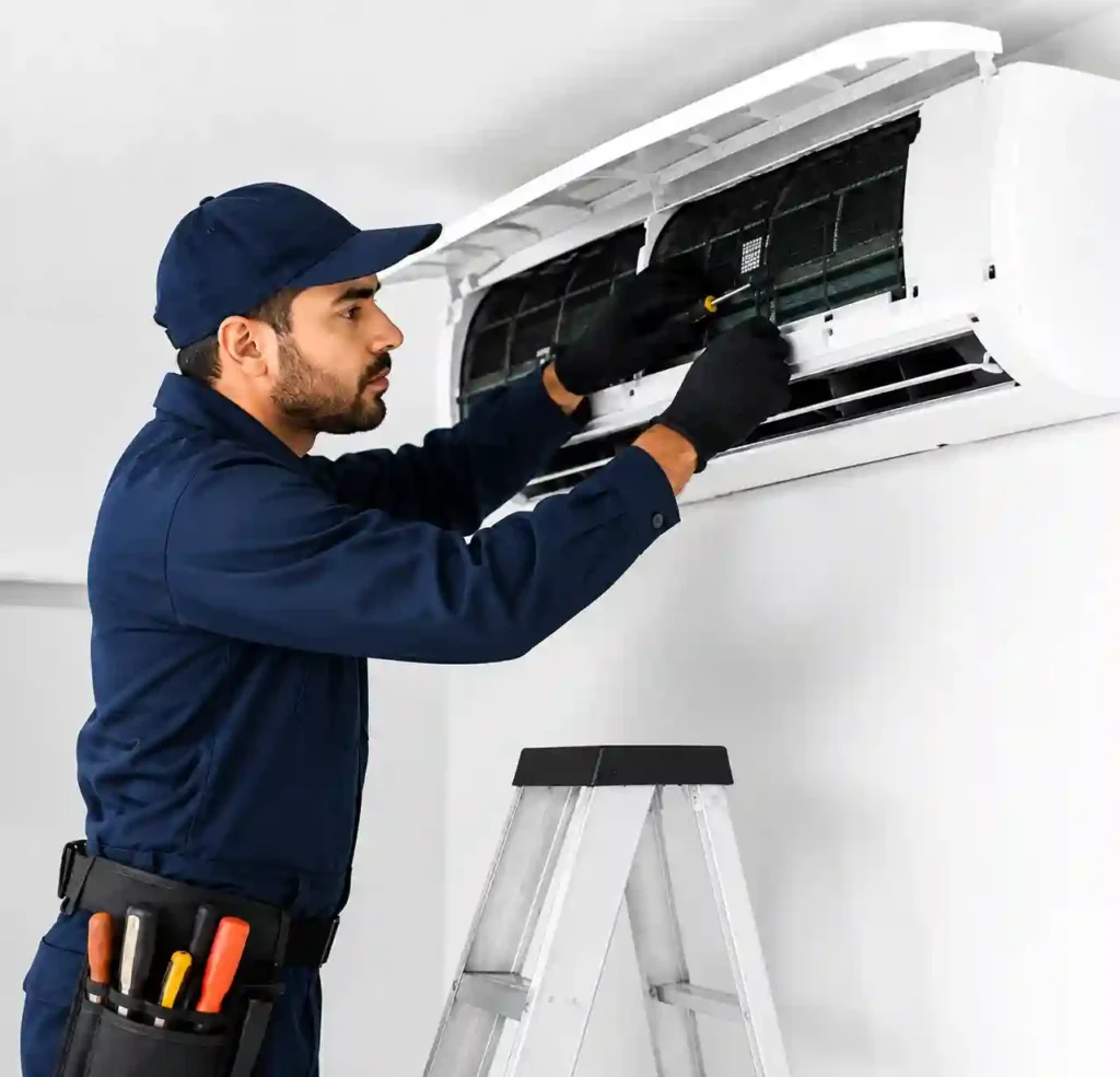 Technician cleaning and servicing an open split air conditioner.